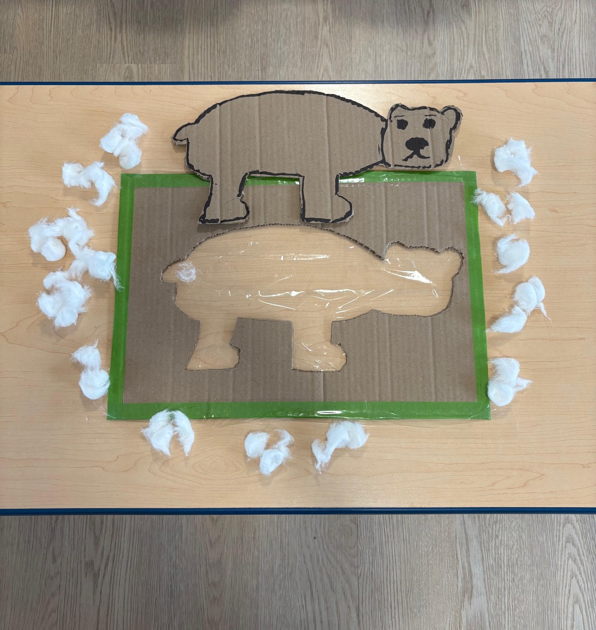 A cardboard bear craft in progress, edged with cotton.