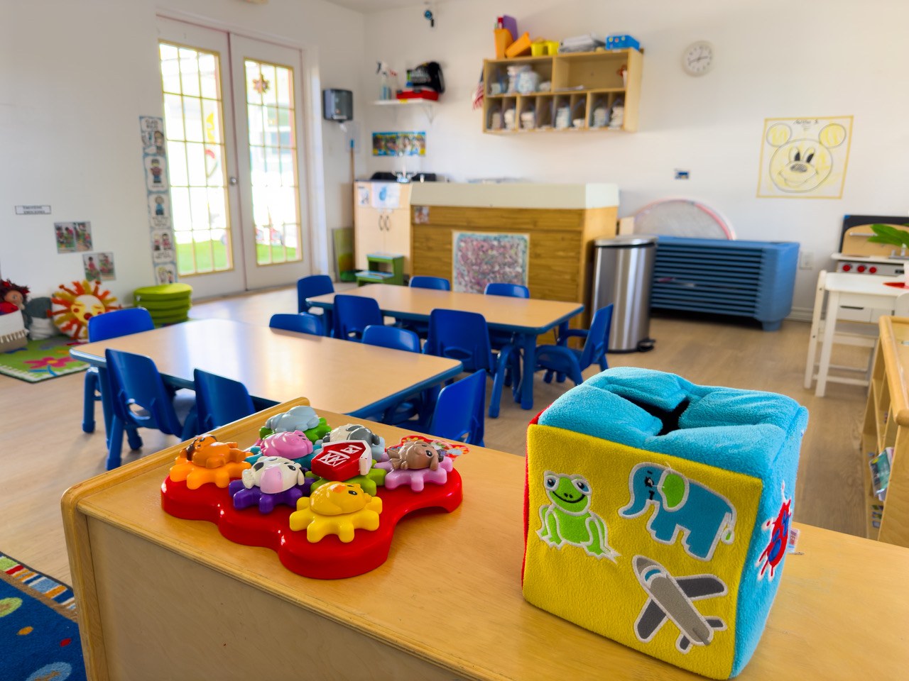 A classroom with blue chairs and toys set out along the counter.