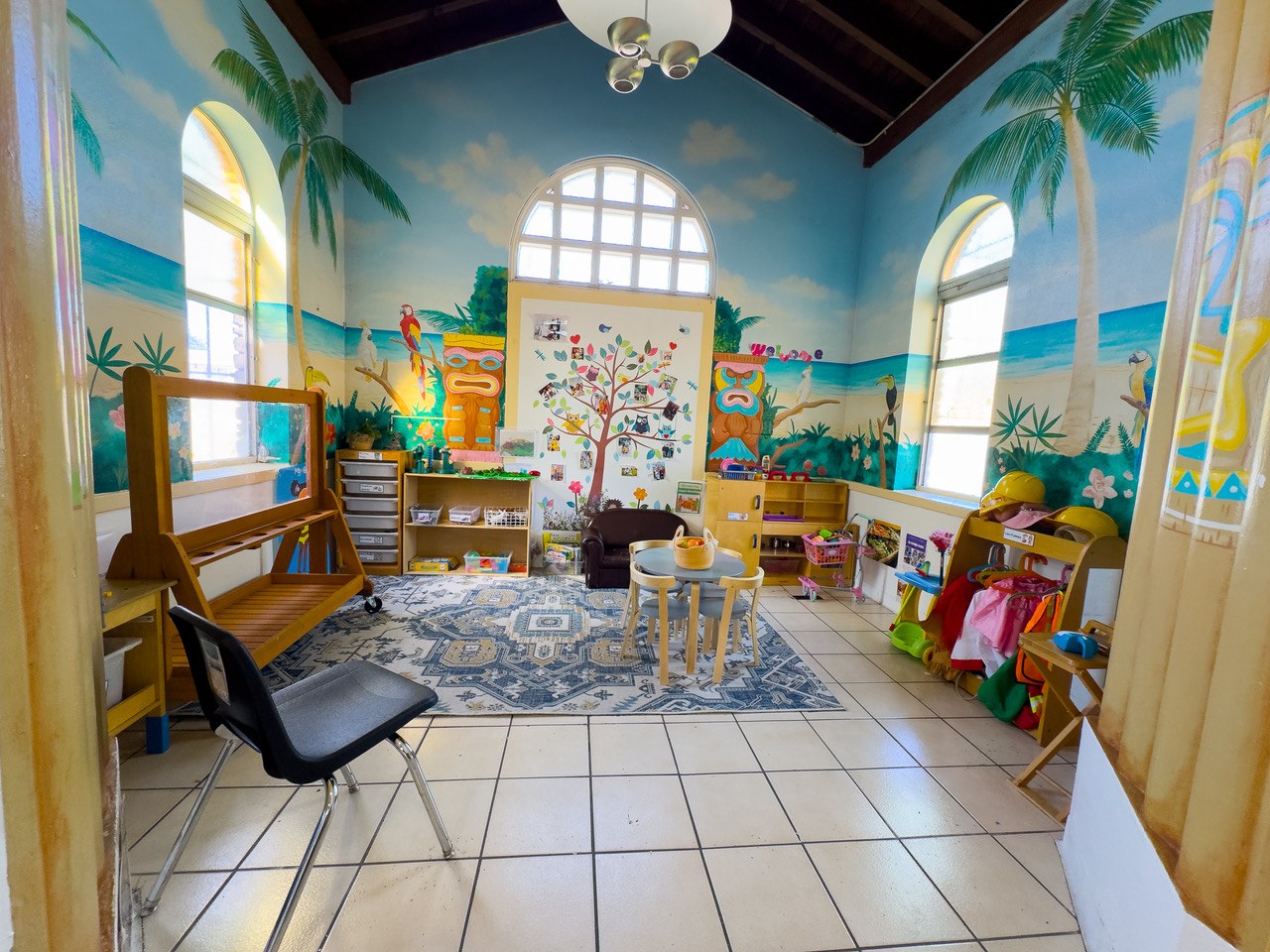 A classroom painted with a tropical beach mural, under arched windows.